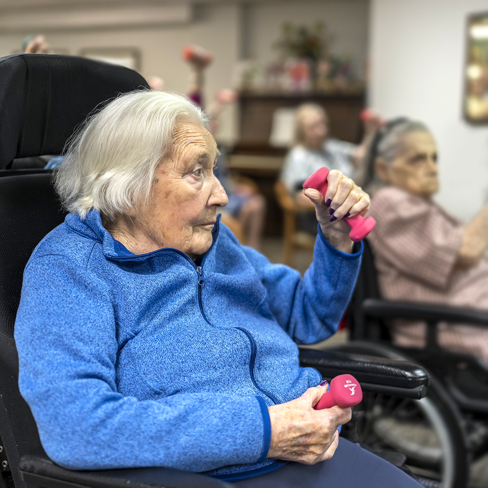 Resident participating in a seated fitness class with hand weights at Atrium Retirement Residence in Orillia, promoting active and healthy living